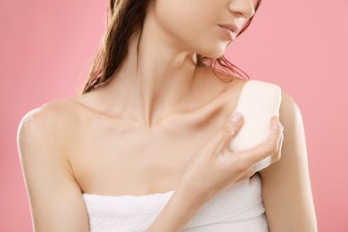 Photo of Woman with foaming soap bar on pink background, closeup