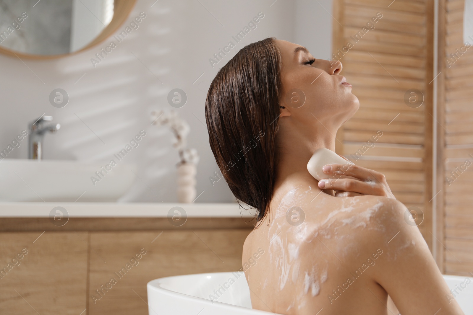 Woman washing body with soap bar in bathroom. Space for text Photo of Woman washing body with soap bar in bathroom. Space for text