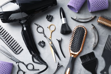 Photo of Different hairdresser's tools on grey table, flat lay