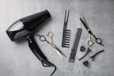 Photo of Different hairdresser's tools on grey table, flat lay