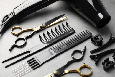 Photo of Different hairdresser's tools on grey table, above view