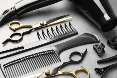 Photo of Different hairdresser's tools on grey table, closeup