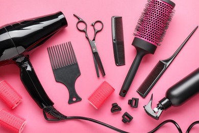 Photo of Different hairdresser's tools on pink background, flat lay