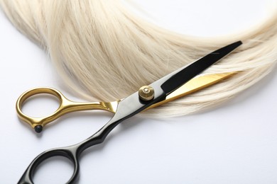 Photo of Hair lock and scissors on white background, above view