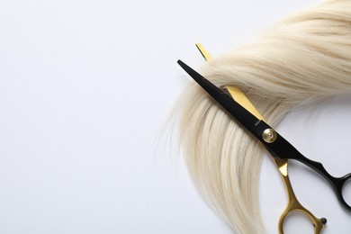 Photo of Hair lock and scissors on white background, top view. Space for text