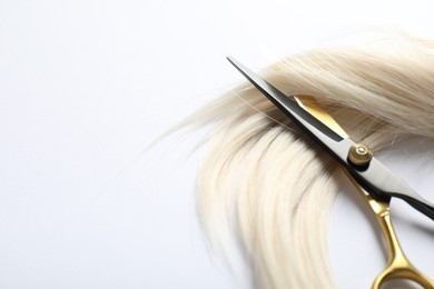 Photo of Hair lock and scissors on white background, above view. Space for text