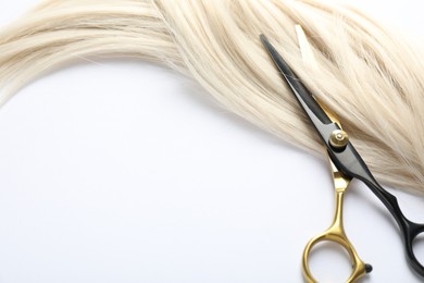 Photo of Hair lock and scissors on white background, above view. Space for text