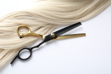 Photo of Hair lock and scissors on white background, above view. Space for text