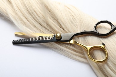 Photo of Hair lock and scissors on white background, above view