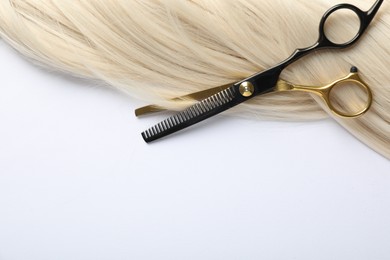 Photo of Hair lock and scissors on white background, top view. Space for text