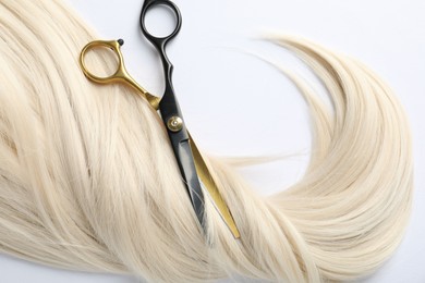 Photo of Hair lock and scissors on white background, flat lay