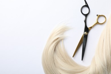 Photo of Hair lock and scissors on white background, flat lay. Space for text