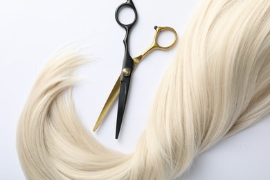 Photo of Hair lock and scissors on white background, flat lay