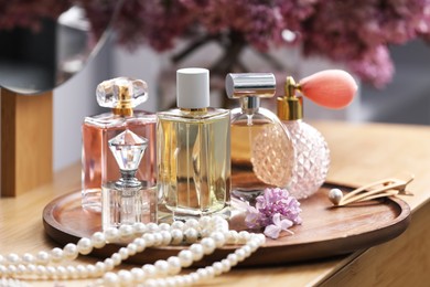 Photo of Bottles of perfumes, accessories and lilac flowers on wooden table, closeup