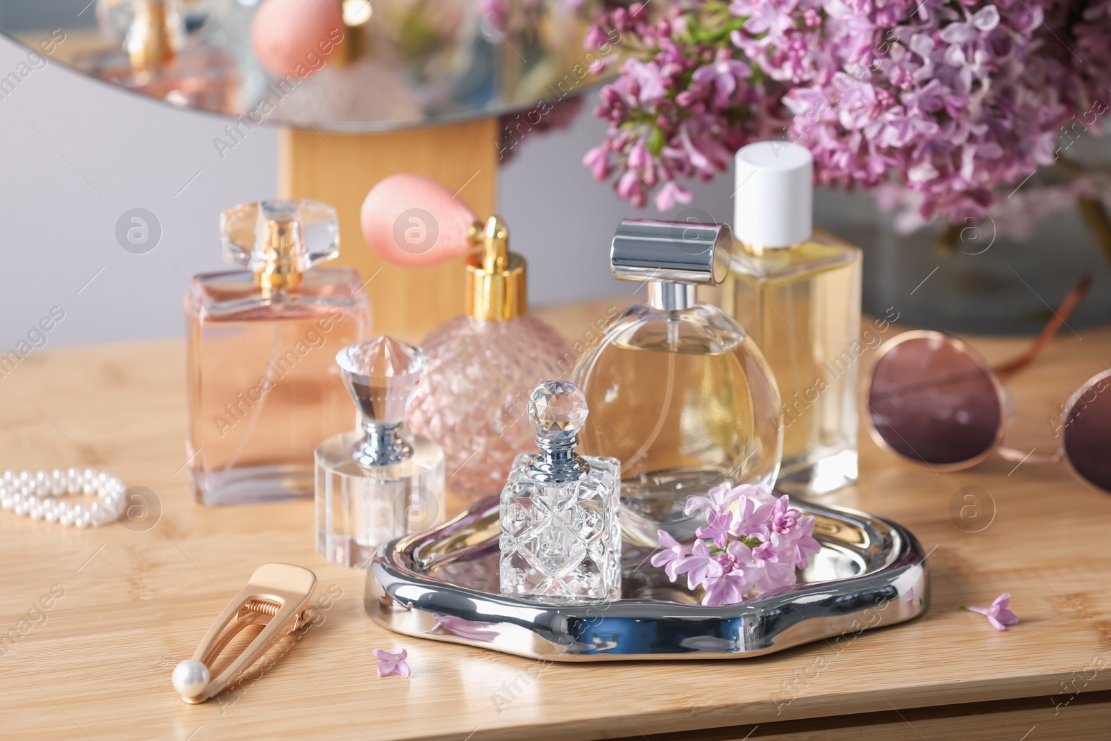 Bottles of perfumes, accessories and lilac flowers on wooden table Photo of Bottles of perfumes, accessories and lilac flowers on wooden table