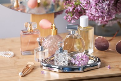 Photo of Bottles of perfumes, accessories and lilac flowers on wooden table