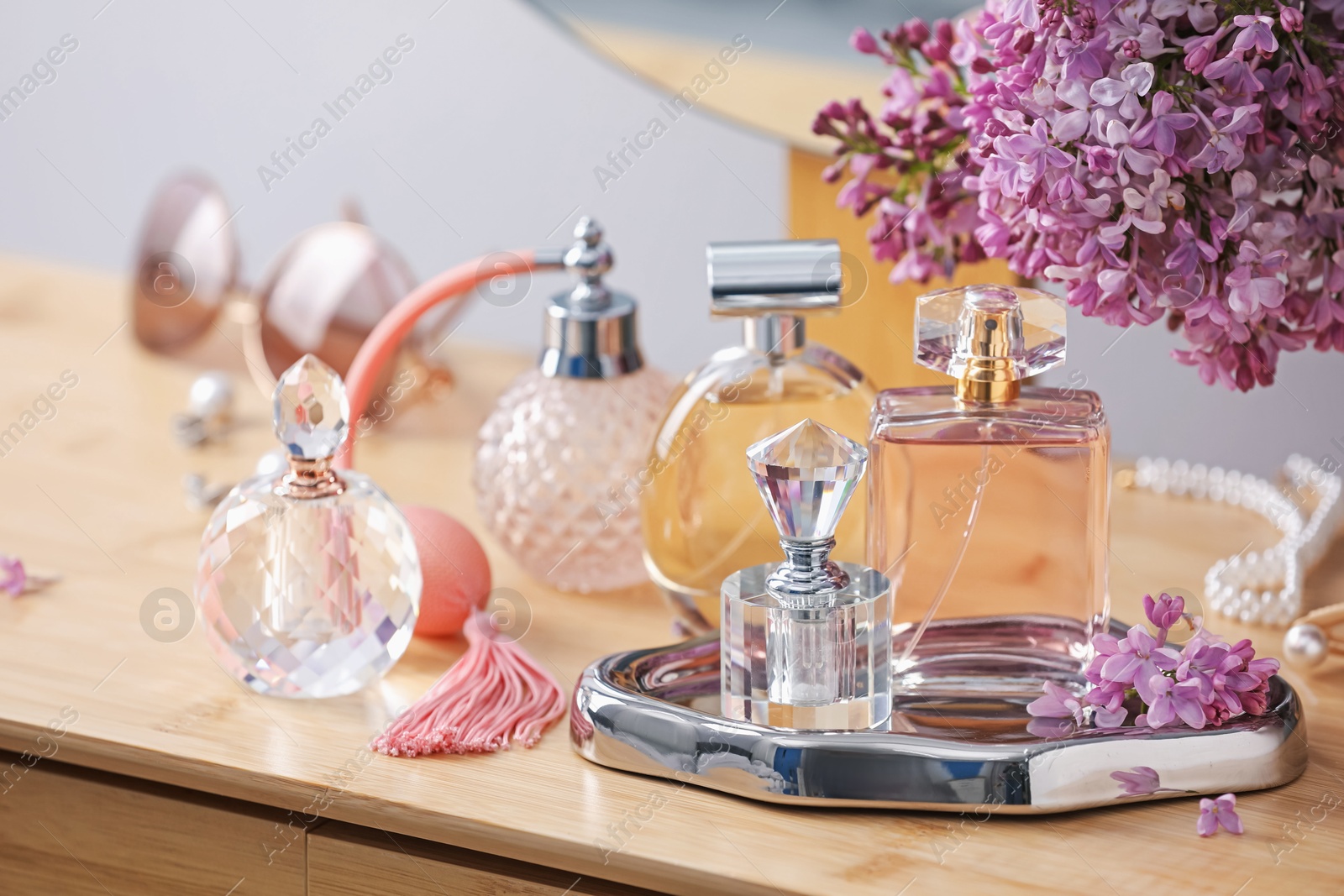 Bottles of perfumes, accessories and lilac flowers on wooden table Photo of Bottles of perfumes, accessories and lilac flowers on wooden table