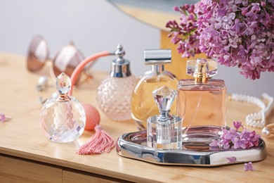 Photo of Bottles of perfumes, accessories and lilac flowers on wooden table