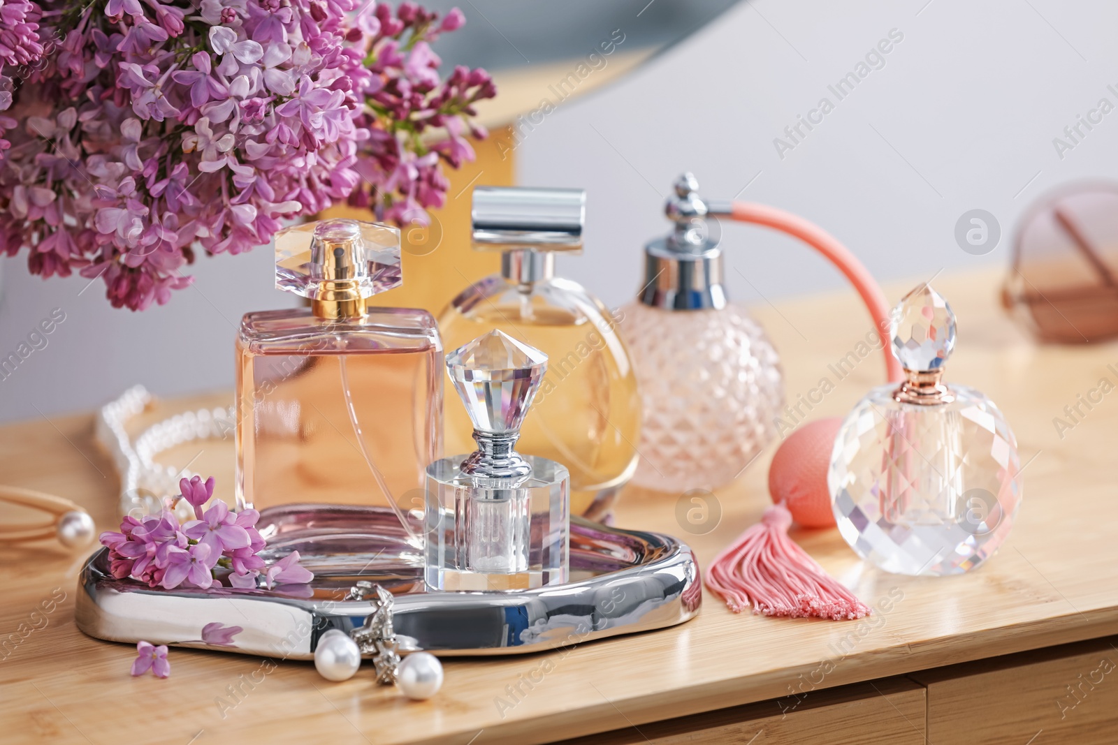 Bottles of perfumes, accessories and lilac flowers on wooden table Photo of Bottles of perfumes, accessories and lilac flowers on wooden table