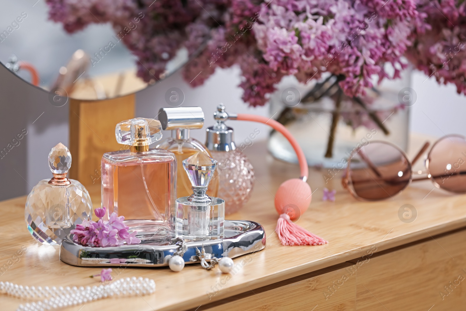 Bottles of perfumes, accessories and lilac flowers on wooden table Photo of Bottles of perfumes, accessories and lilac flowers on wooden table