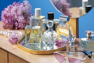 Photo of Bottles of perfumes, accessories and lilac flowers on wooden table