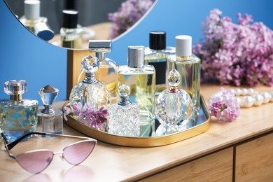 Photo of Bottles of perfumes, accessories and lilac flowers on wooden table