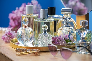 Photo of Bottles of perfumes, accessories and lilac flowers on wooden table, closeup