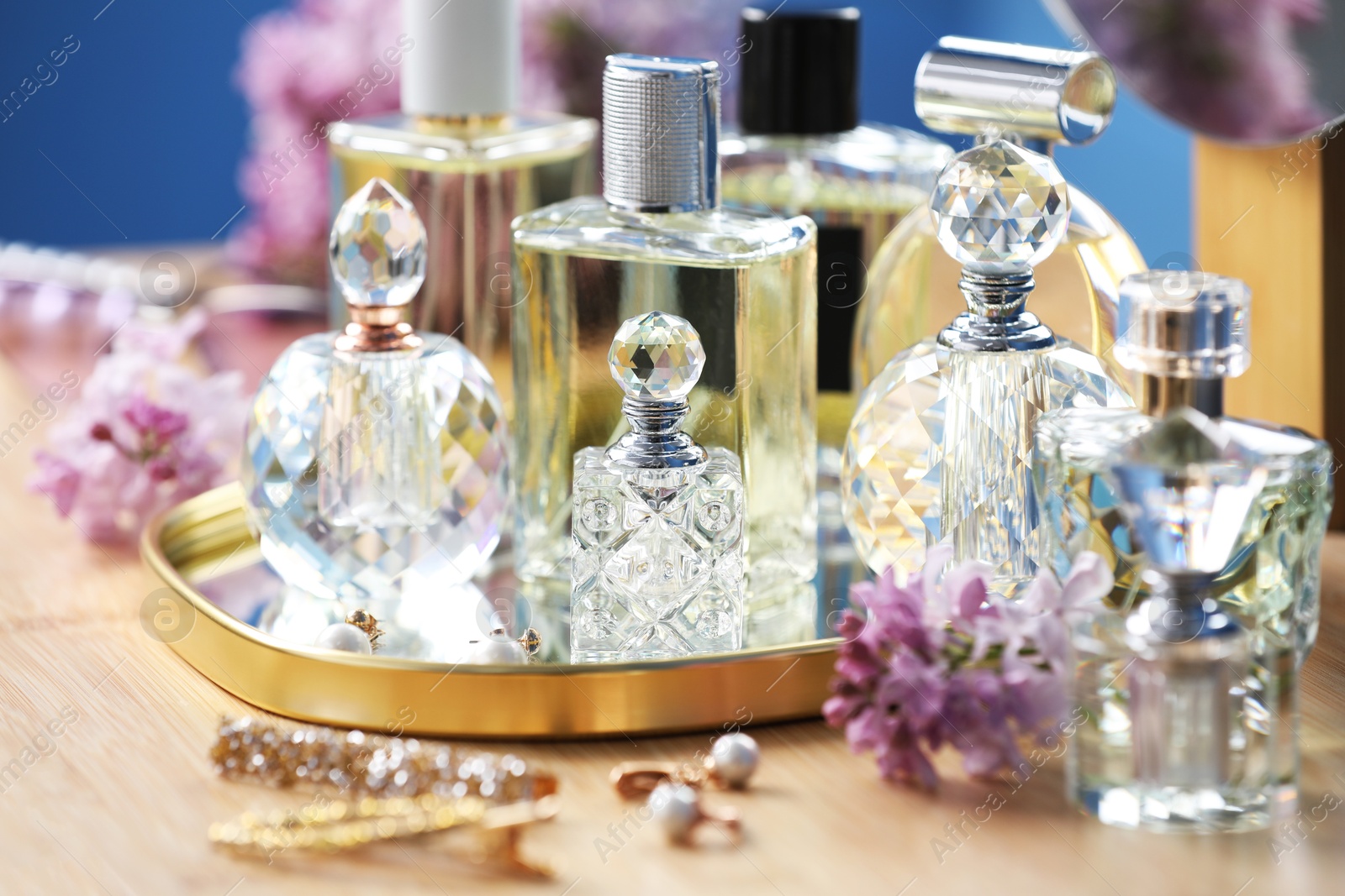 Bottles of perfumes, accessories and lilac flowers on wooden table, closeup Photo of Bottles of perfumes, accessories and lilac flowers on wooden table, closeup