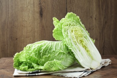 Photo of Whole and cut Chinese cabbages on wooden table