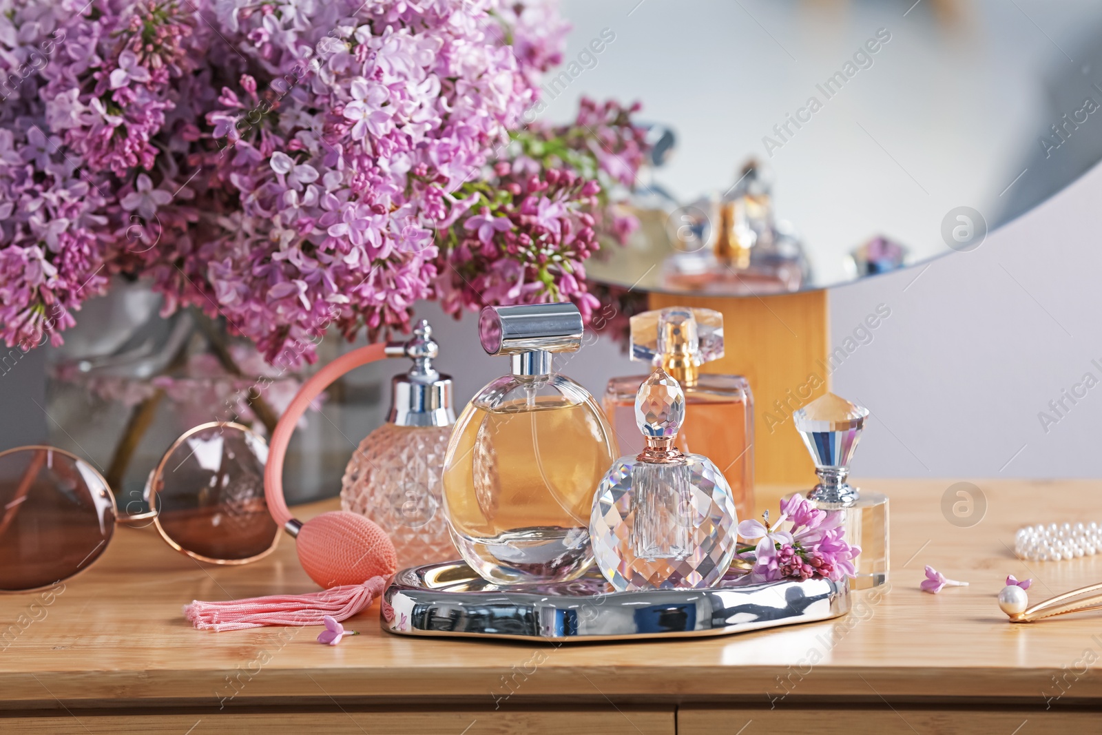 Bottles of perfumes, accessories and lilac flowers on wooden table Photo of Bottles of perfumes, accessories and lilac flowers on wooden table