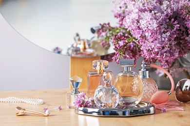 Photo of Bottles of perfumes, accessories and lilac flowers on wooden table