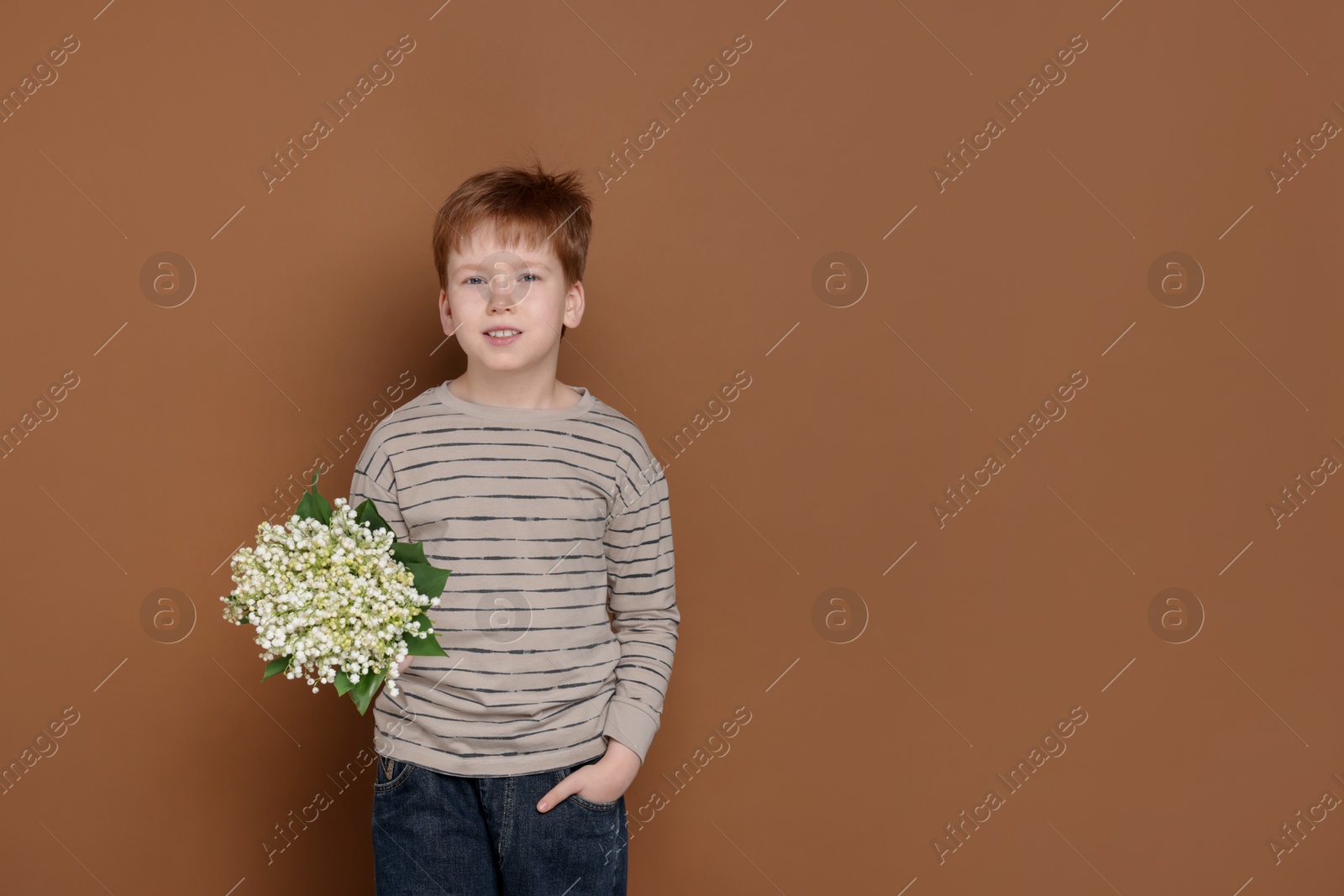 Boy with bouquet of beautiful lily-of-the-valley flowers on brown background. Space for text Photo of Boy with bouquet of beautiful lily-of-the-valley flowers on brown background. Space for text