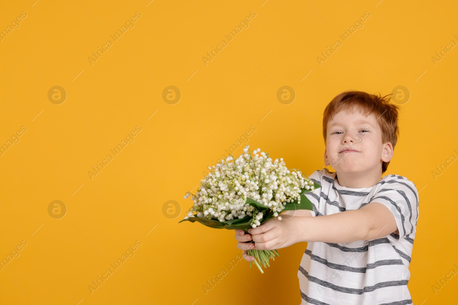 Boy with bouquet of beautiful lily-of-the-valley flowers on yellow background. Space for text Photo of Boy with bouquet of beautiful lily-of-the-valley flowers on yellow background. Space for text