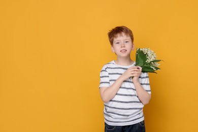 Photo of Boy with bouquet of beautiful lily-of-the-valley flowers on yellow background. Space for text