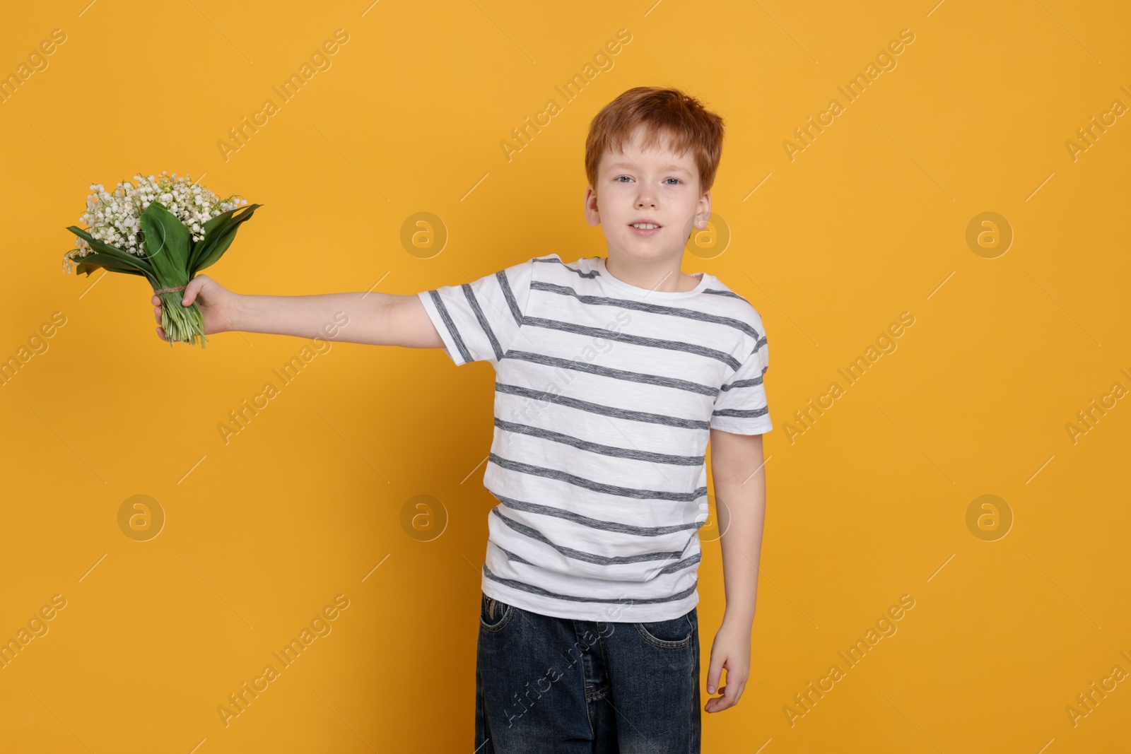 Boy with bouquet of beautiful lily-of-the-valley flowers on yellow background Photo of Boy with bouquet of beautiful lily-of-the-valley flowers on yellow background