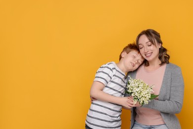 Photo of Boy giving his mother beautiful bouquet of lily-of-the-valley flowers on yellow background. Space for text