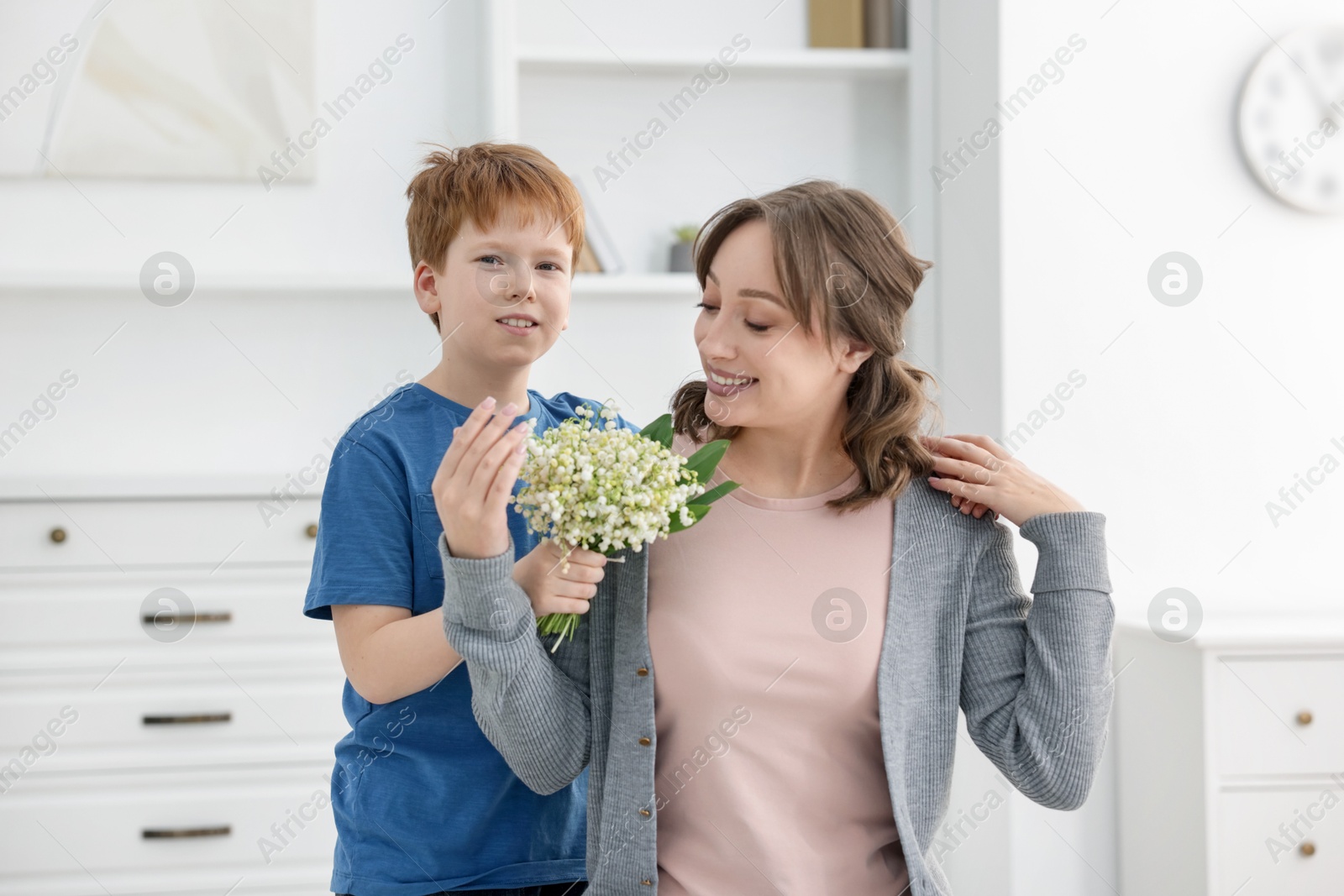 Boy giving his mother beautiful bouquet of lily-of-the-valley flowers at home Photo of Boy giving his mother beautiful bouquet of lily-of-the-valley flowers at home