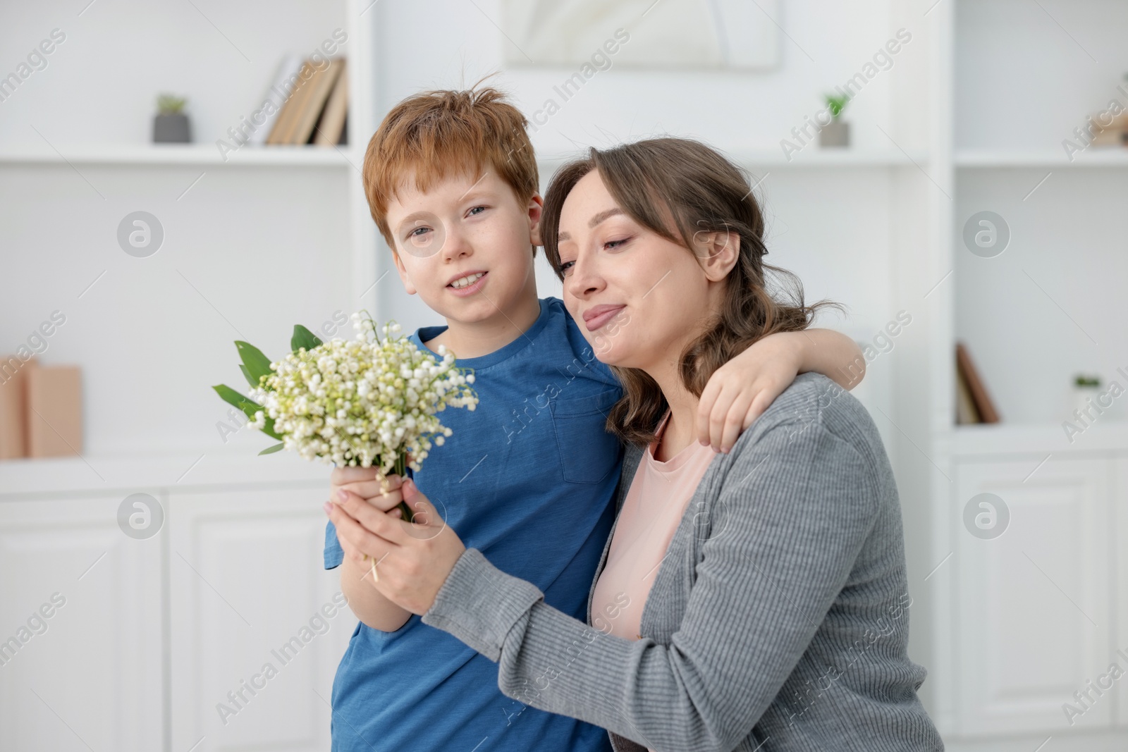 Boy giving his mother beautiful bouquet of lily-of-the-valley flowers at home Photo of Boy giving his mother beautiful bouquet of lily-of-the-valley flowers at home