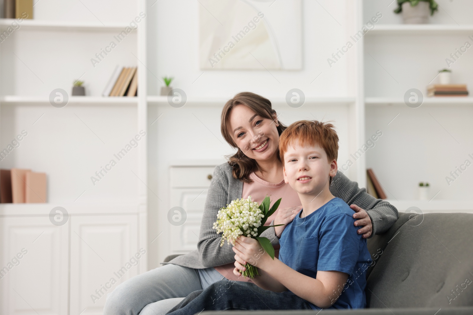 Boy giving his mother beautiful bouquet of lily-of-the-valley flowers at home. Space for text Photo of Boy giving his mother beautiful bouquet of lily-of-the-valley flowers at home. Space for text