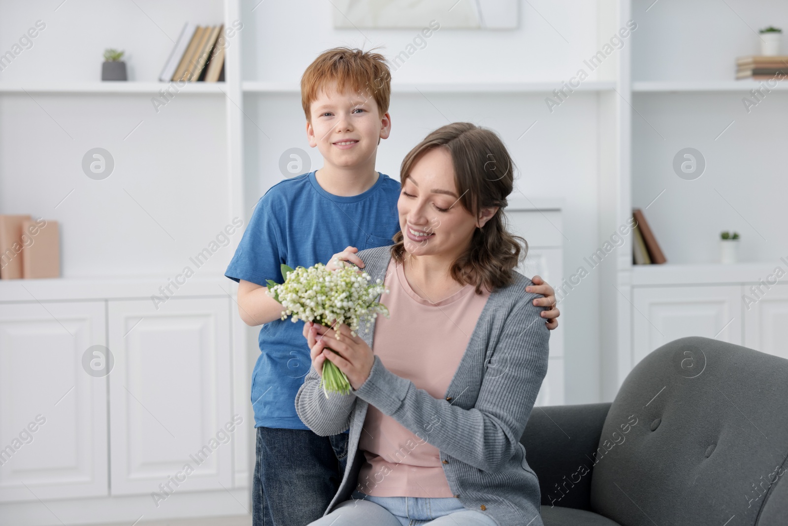 Boy giving his mother beautiful bouquet of lily-of-the-valley flowers at home Photo of Boy giving his mother beautiful bouquet of lily-of-the-valley flowers at home