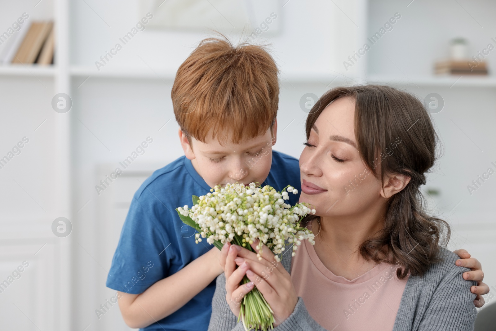 Boy giving his mother beautiful bouquet of lily-of-the-valley flowers at home Photo of Boy giving his mother beautiful bouquet of lily-of-the-valley flowers at home