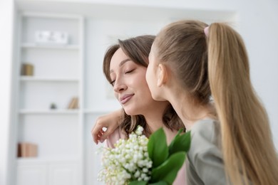 Photo of Girl giving her mother beautiful bouquet of lily-of-the-valley flowers at home