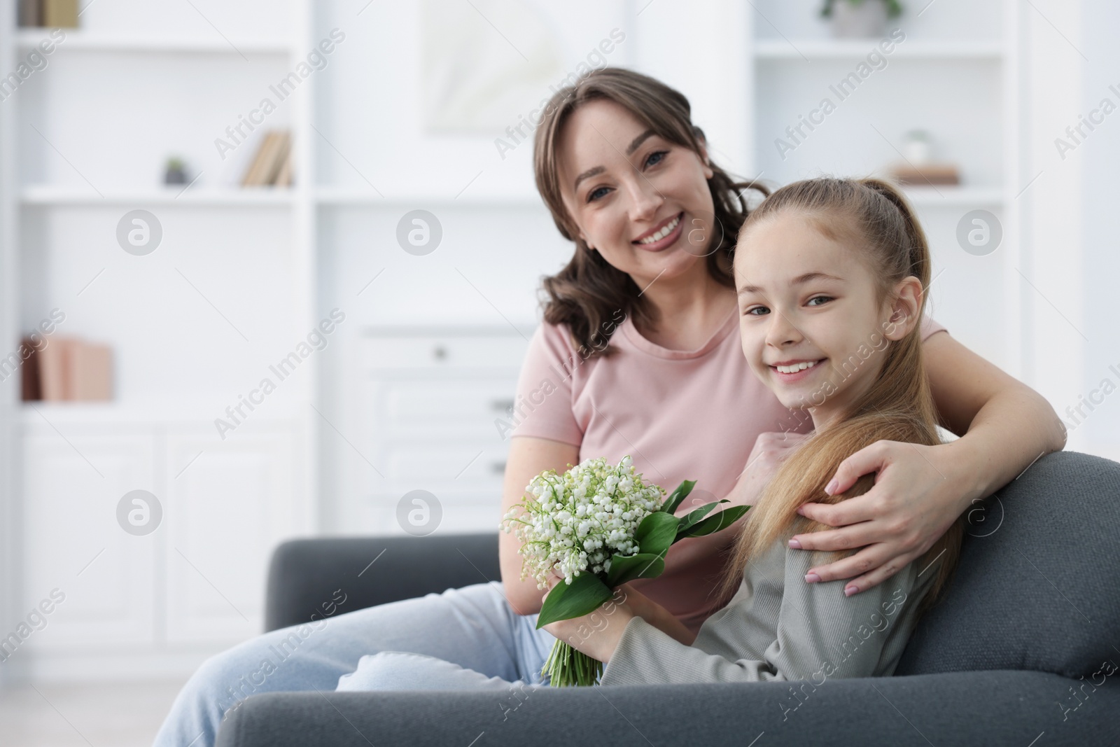 Girl giving her mother beautiful bouquet of lily-of-the-valley flowers at home. Space for text Photo of Girl giving her mother beautiful bouquet of lily-of-the-valley flowers at home. Space for text
