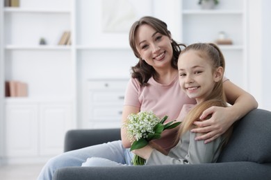 Photo of Girl giving her mother beautiful bouquet of lily-of-the-valley flowers at home. Space for text