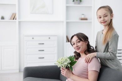 Photo of Girl giving her mother beautiful bouquet of lily-of-the-valley flowers at home. Space for text