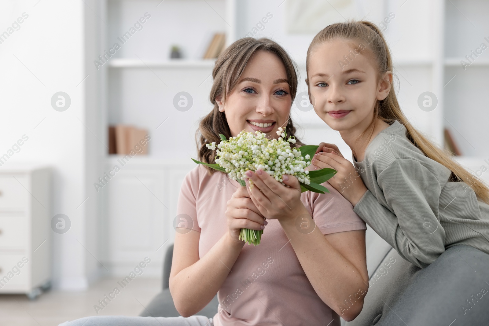 Girl giving her mother beautiful bouquet of lily-of-the-valley flowers at home Photo of Girl giving her mother beautiful bouquet of lily-of-the-valley flowers at home