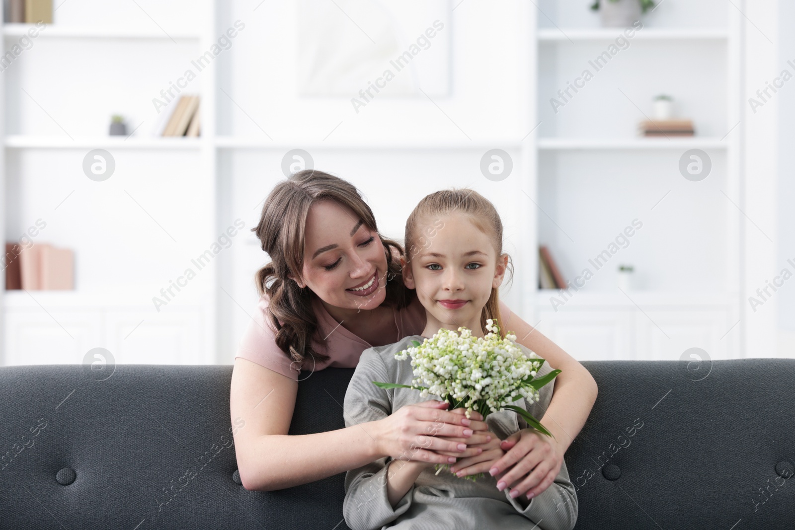 Girl giving her mother beautiful bouquet of lily-of-the-valley flowers at home Photo of Girl giving her mother beautiful bouquet of lily-of-the-valley flowers at home