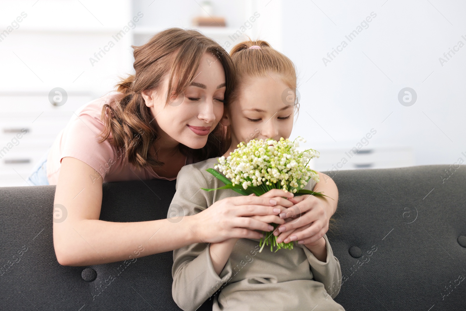 Girl giving her mother beautiful bouquet of lily-of-the-valley flowers at home Photo of Girl giving her mother beautiful bouquet of lily-of-the-valley flowers at home