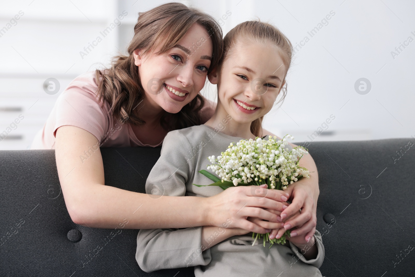 Girl giving her mother beautiful bouquet of lily-of-the-valley flowers at home Photo of Girl giving her mother beautiful bouquet of lily-of-the-valley flowers at home