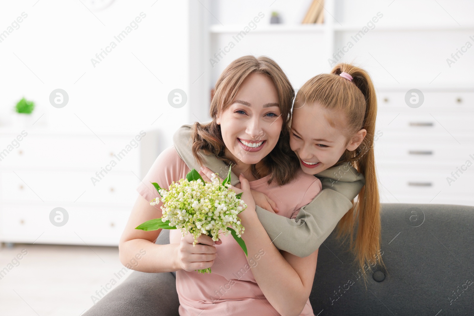 Girl giving her mother beautiful bouquet of lily-of-the-valley flowers at home Photo of Girl giving her mother beautiful bouquet of lily-of-the-valley flowers at home
